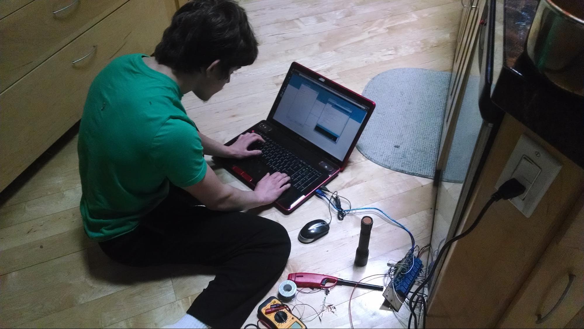 Me sitting on the floor with my laptop programming the dishasher controller